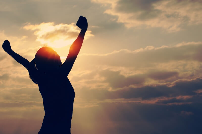 woman open arms under the sunrise at seaside 