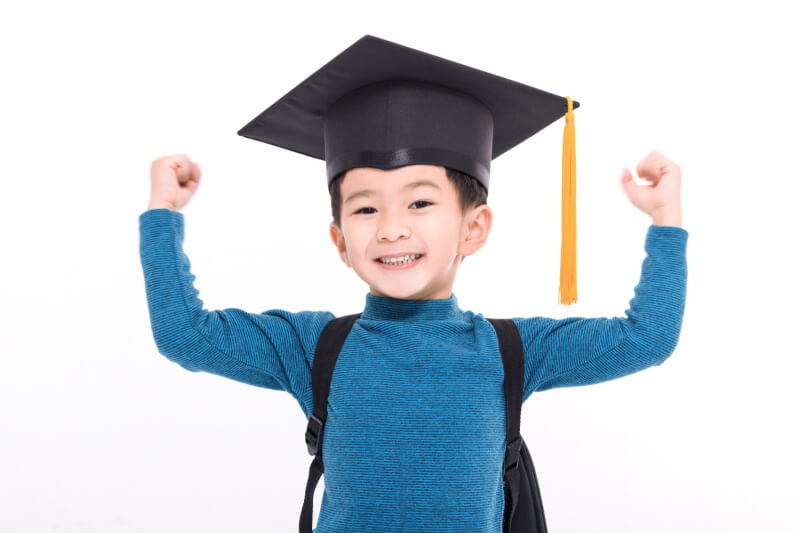 young child happy showing strength and wearing graduation hat