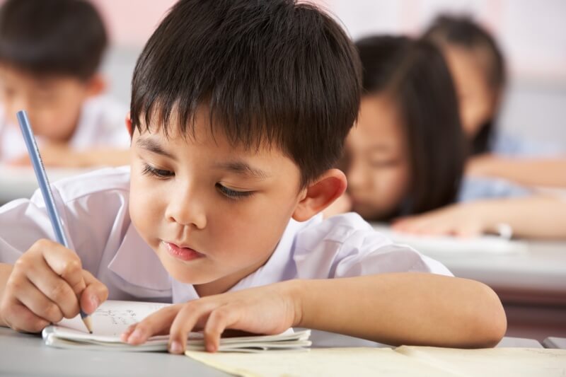 young boy holding pencil learning how to write