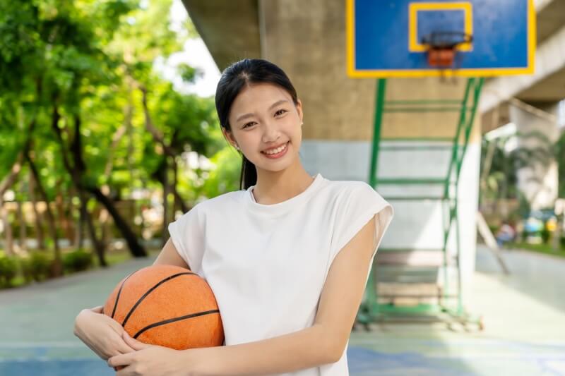 f asian teenager girl basketball player holding a basketball ball