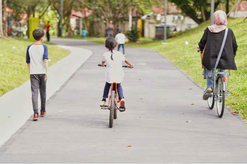 family having fun cycling and jogging at the park