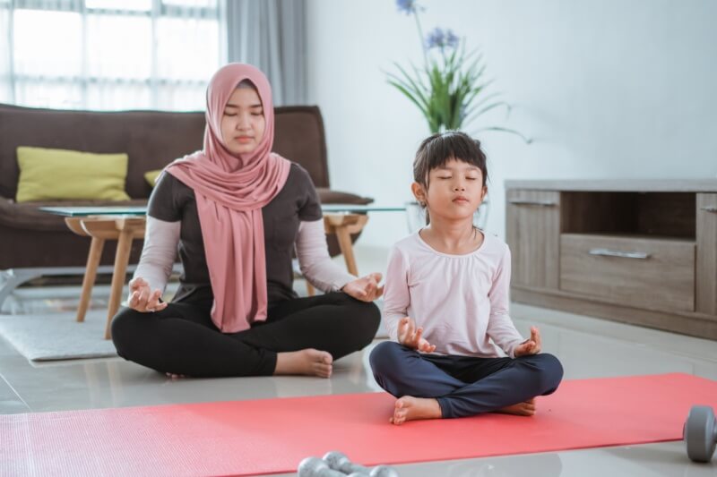  woman and daughter doing yoga exercise and sport at home together