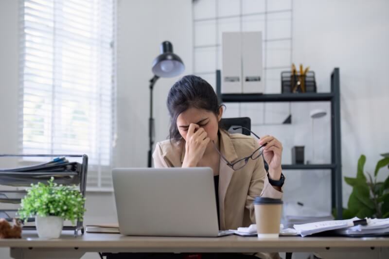woman sitting in front of laptop overworked and tired