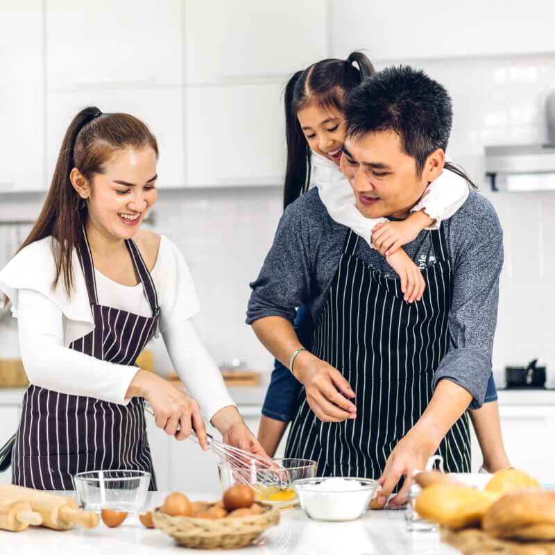 family making meals in the kitchen father carrying daughter on his back