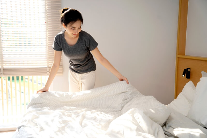 woman cleaning out the bed in the morning