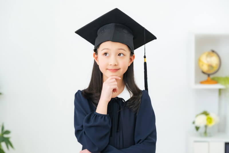 little girl in graduation ceremony robe thinking about her future