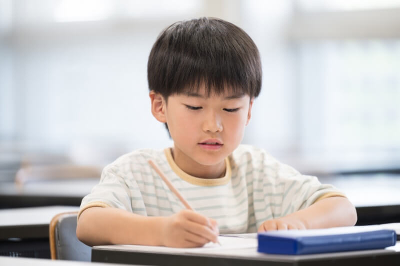 young boy on the table doing homework