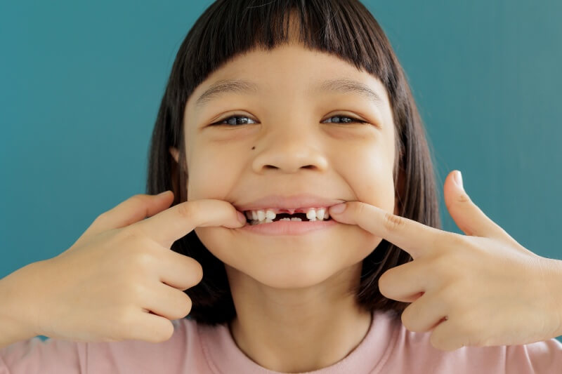 asian young girl showing wobbly tooth smiling and happy