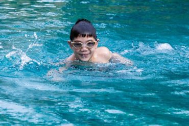 child swimming with goggles in the pool