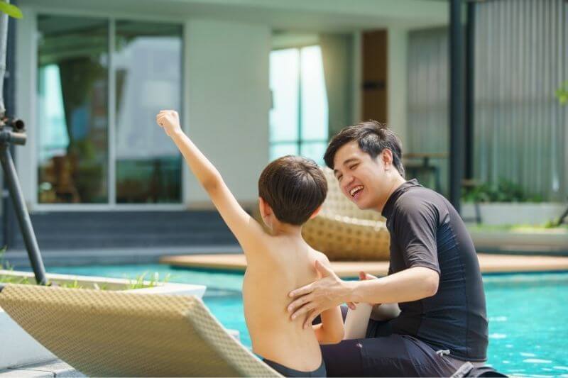 father and son by the swimming pool