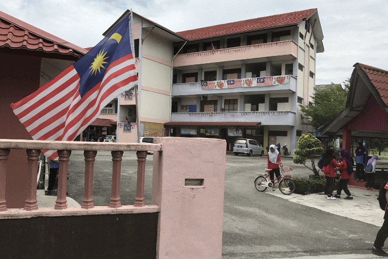  Malaysia flag or 'Jalur Gemilang' with pupils in school area.