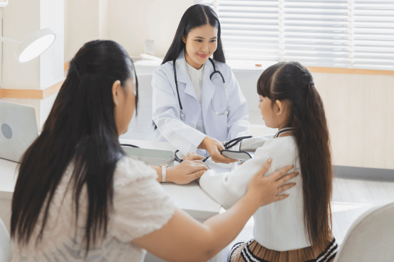 female doctor with stethoscope examining child patient with her mother in hospital