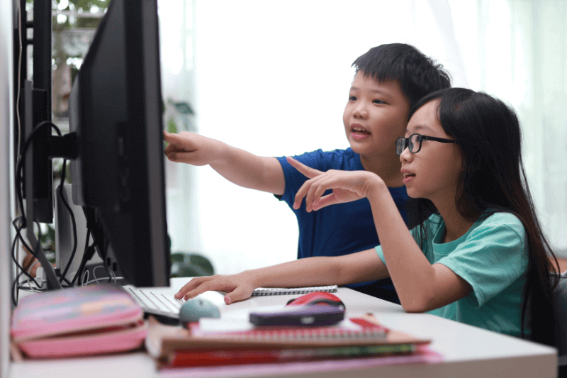  sibling sharing using a computer at home. E-learning and home schooling concept.