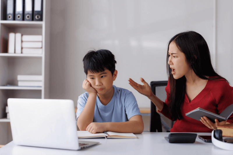  mother scolding her son for focusing on the laptop instead of completing his homework, highlighting the challenges of parenting and education