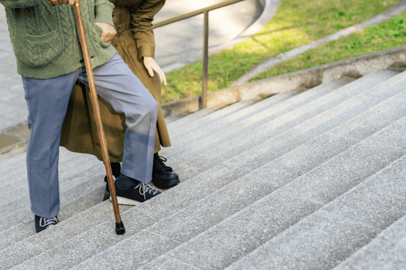 Senior couple: man climbing stairs with a cane and woman supporting him