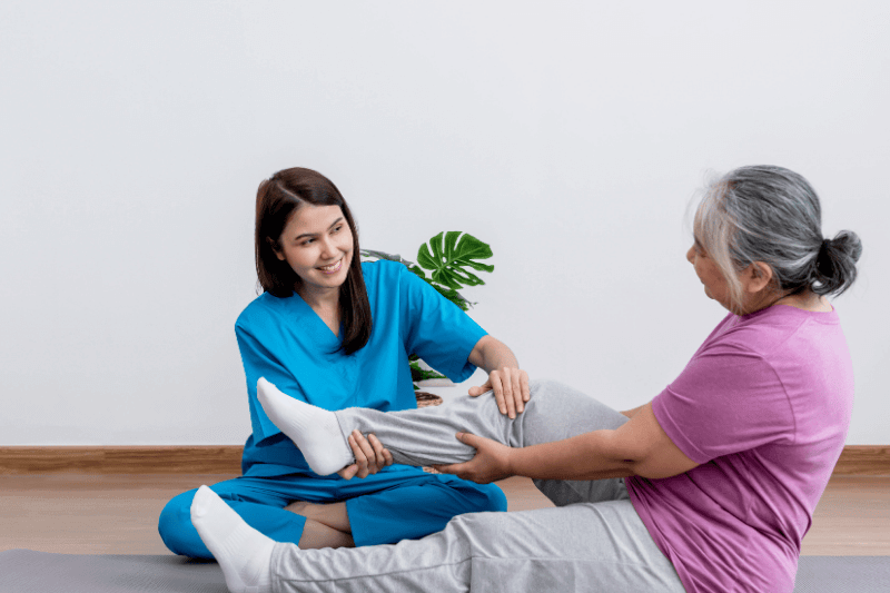 Physical therapist Asian woman, doing leg physiotherapy for elderly woman, to treat osteoarthritis and nerve pain in the leg,