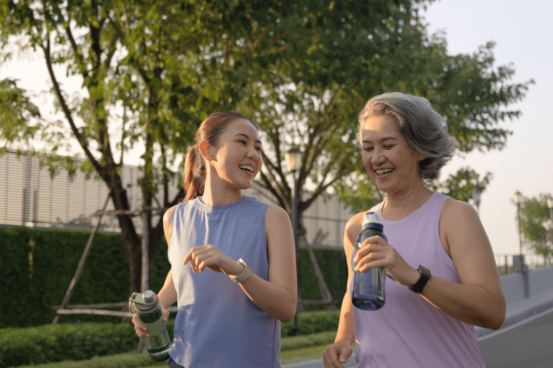 Young adult child workout outdoor public park run walk hold water bottle with mature middle age old mum