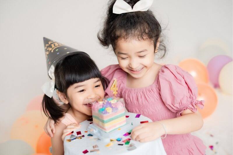 two girls enjoying their birthday celebration with birthday cake