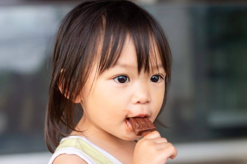 young asian toddler eating chocolate