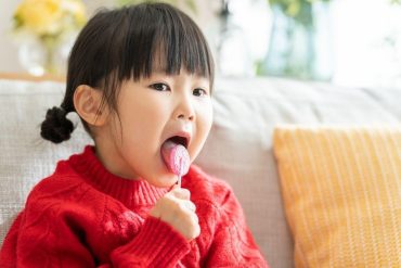Asian child licking a lollipop