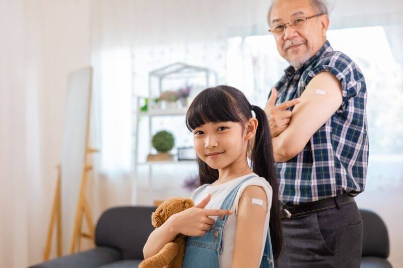 Vaccination in the shoulder of child and grandfather