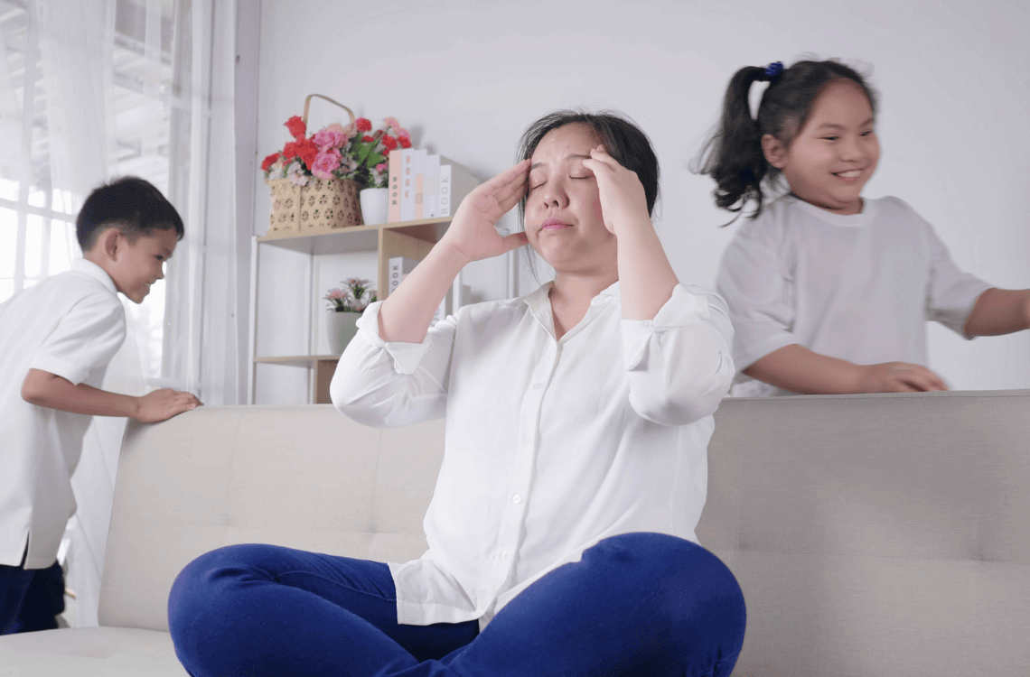 Kids tired and running near upset mother sitting at couch.
