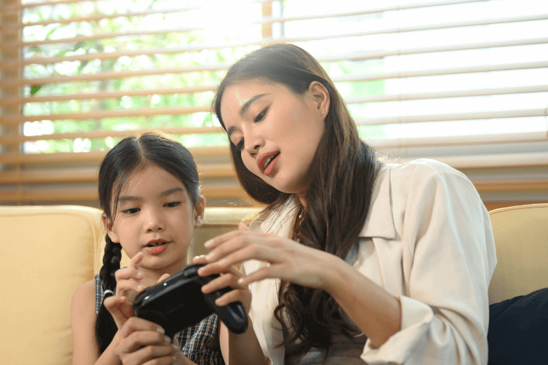 Parent and daughter spending quality time together, learning and playing video games.
