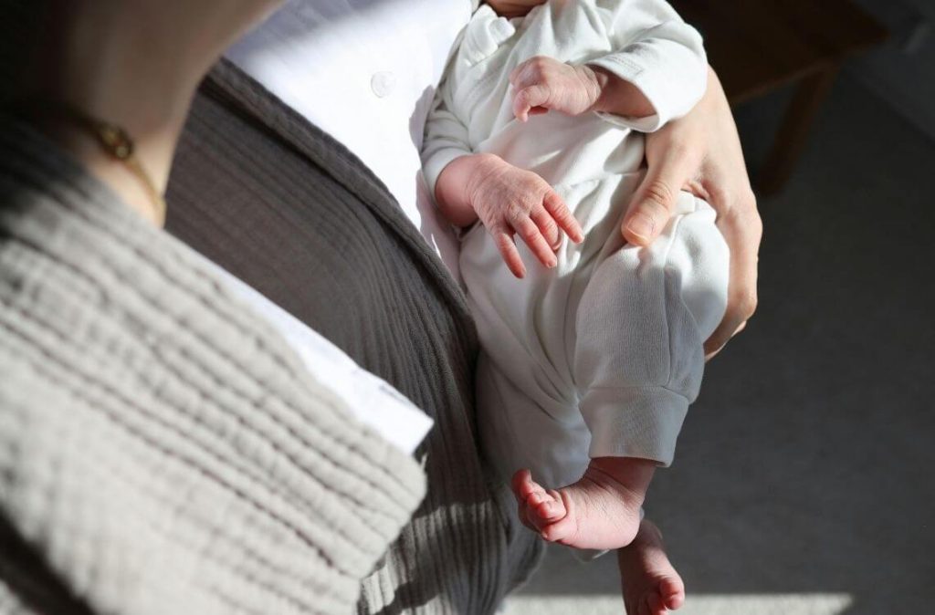 mother carrying young infant in arm