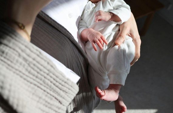 mother carrying young infant in arm