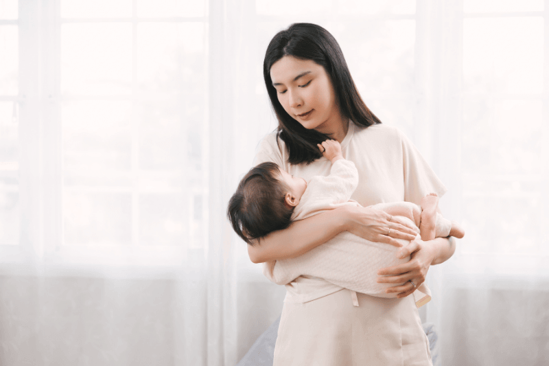mother carrying infant in arm looking lovingly enjoying motherhood