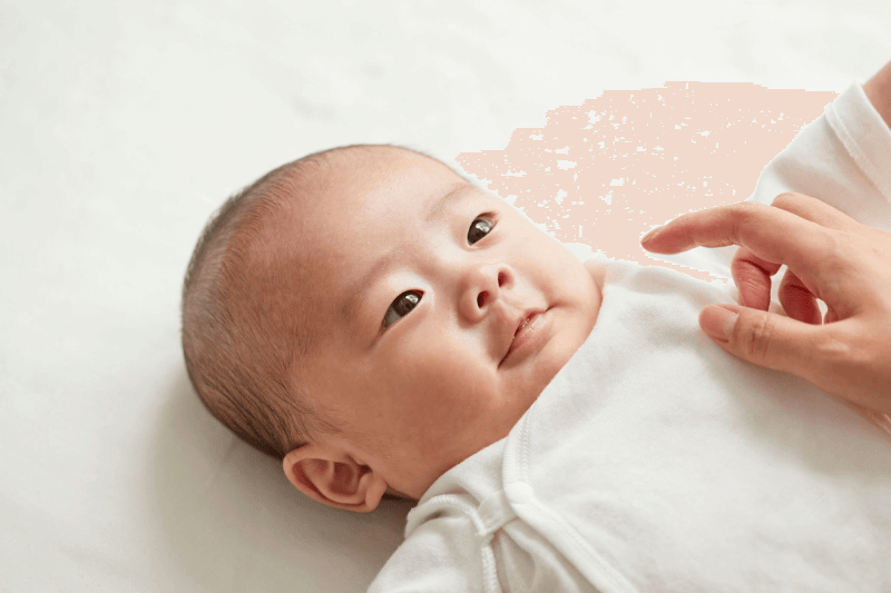 infant child lying down on mattress and looking at parent from top view