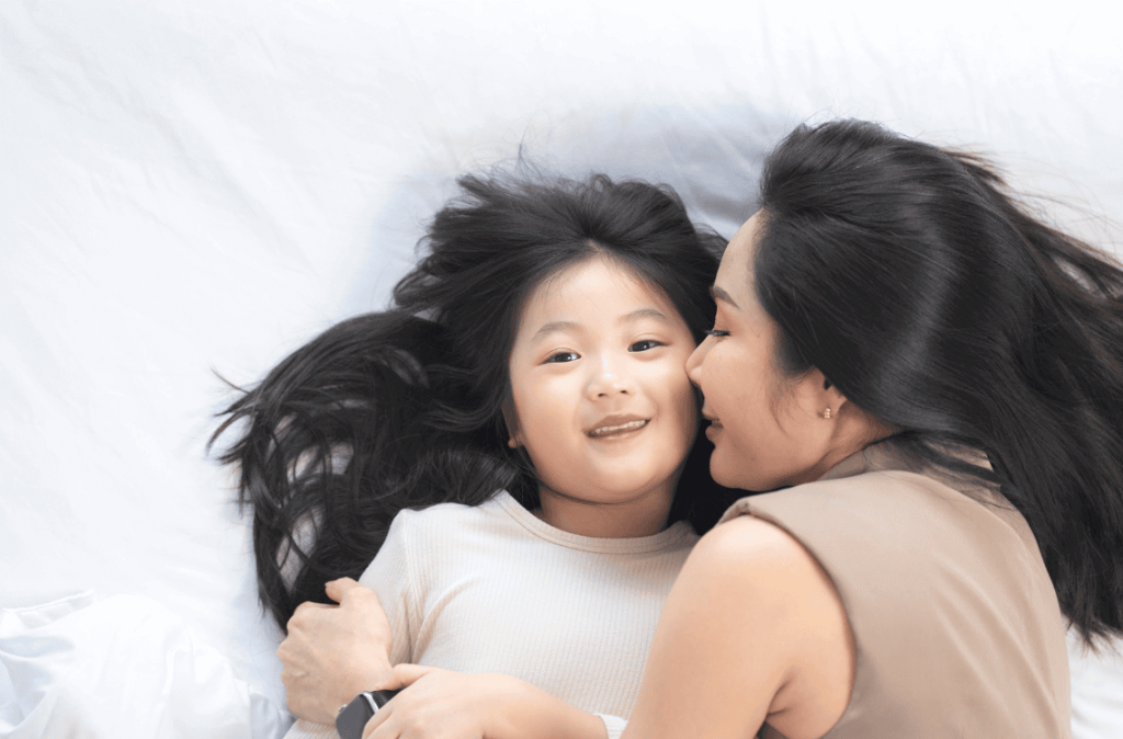 joyful mother and daughter laughing together while lying on a bed