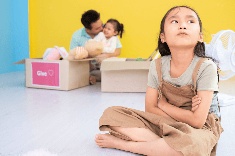 Unhappy little girl feeling jealous while father spending time with her baby sister at home
