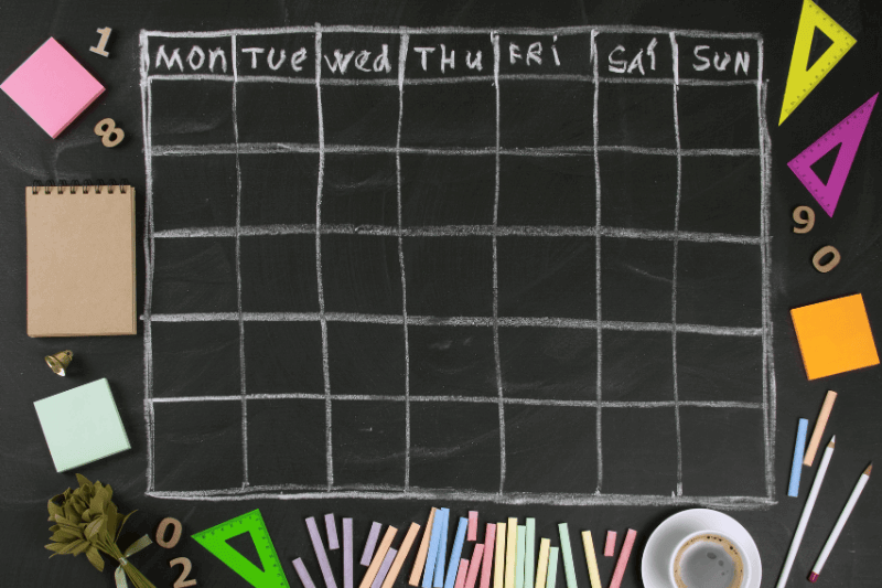 Grid timetable schedule with stationery on black chalkboard background