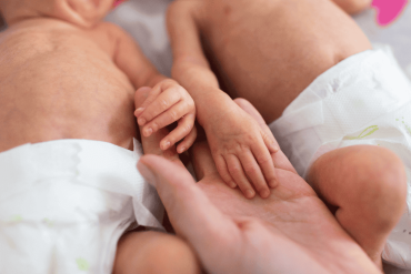 mother holding premature twins hands