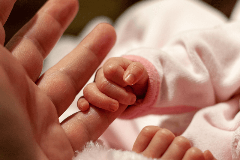 premature baby fingers holding on to mother