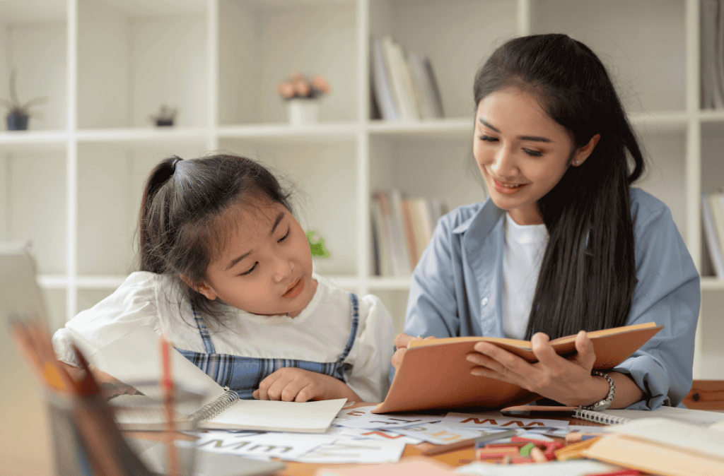 mom is helping with homework and teaching English to her little daughter at home on the weekend