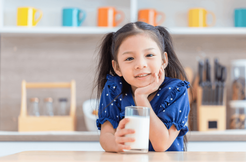 little girl holding cup of milk
