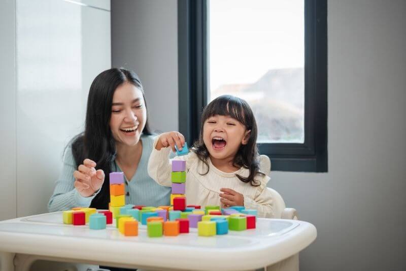 young girl learning and growing with her mother playing blocks
