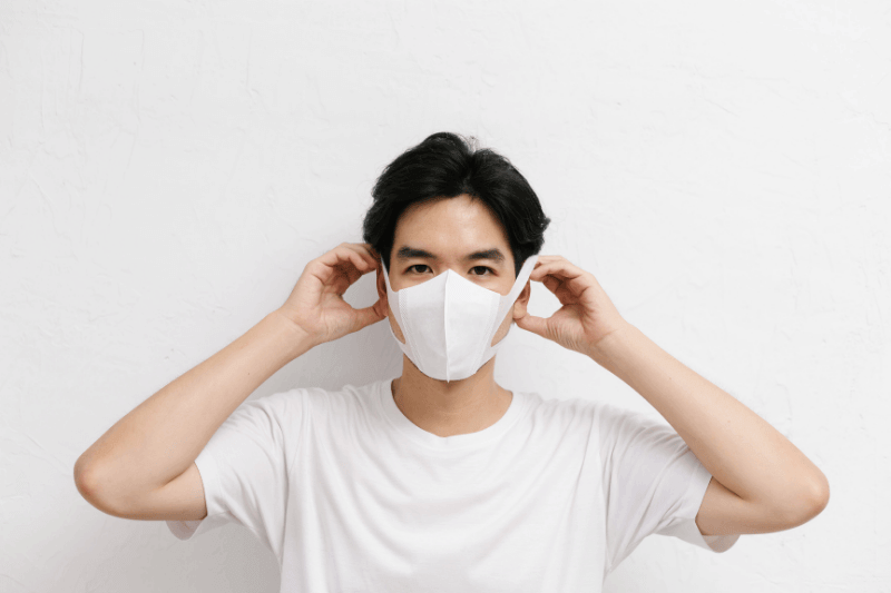 Young asian male wearing medical face mask to protect corona virus, studio portrait.