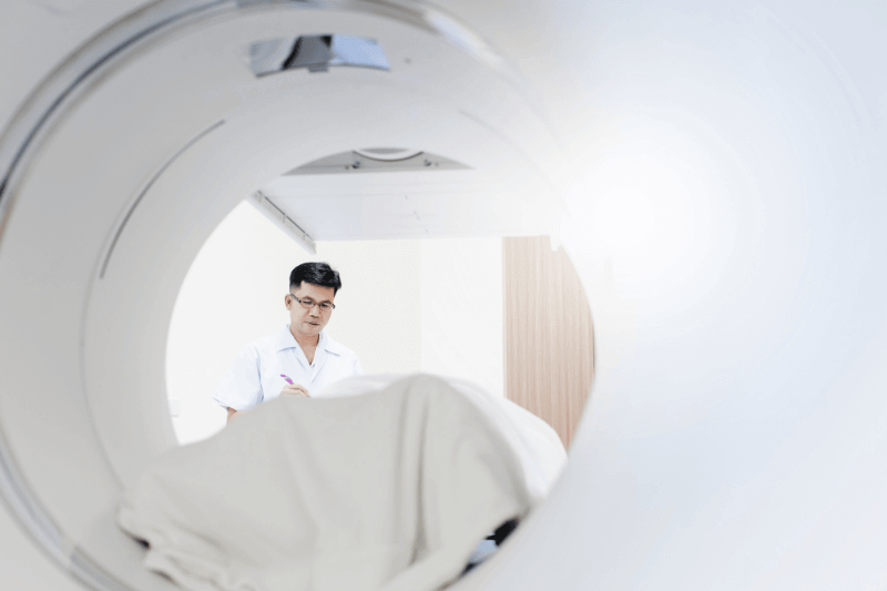 Asian radiologist control and adjust CT scanner machine in x-ray room
