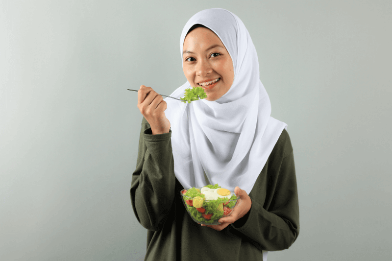 Asian Muslim Woman Wearing a Hijab Enjoys Eating Healthy Yummy Salad Bowl
