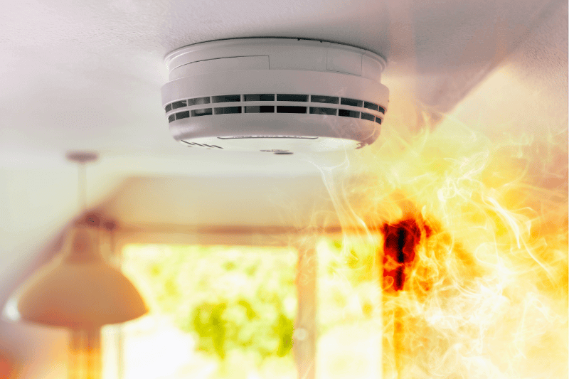 Smoke detector and interlinked fire alarm on ceiling in action background with copy space