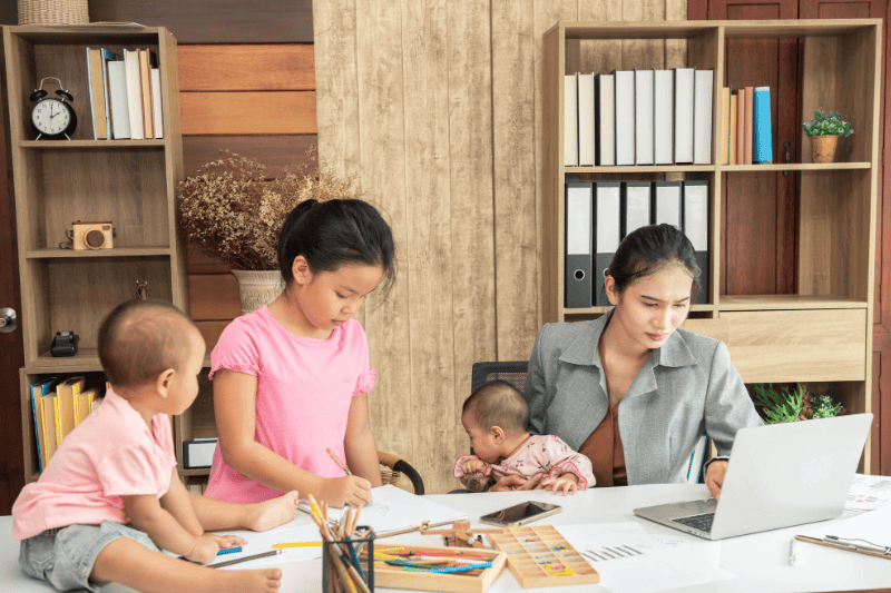 woman trying to work while baby sitting three kids