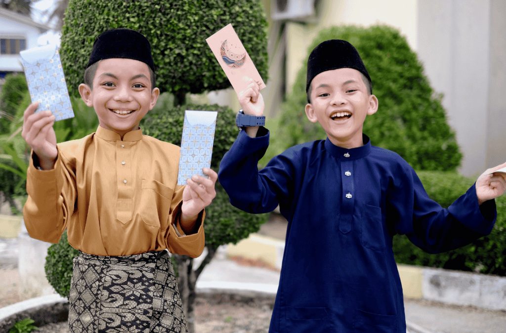 The Malay boys wearing Malay traditional cloth or Baju Melayu showing their happiness reaction after received money pocket during Eid Fitri or Hari Raya celebration