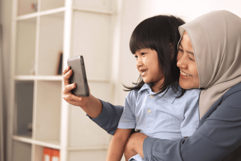 mother and daughter making video call on her phone, distant family gathering via online telecomuting app concept
