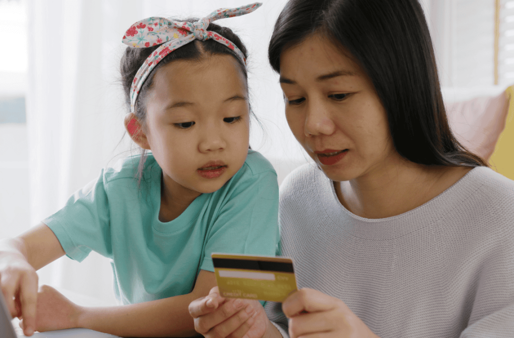 Young girl little kid help mom pay bills online
