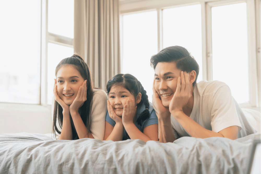 family of three on bed enjoying quiet time together relaxing