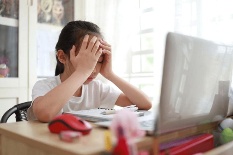Portrait of sad teenage Asian girl looks at laptop upset by bad news, negative bullying message, troubled with problem online or email notification.