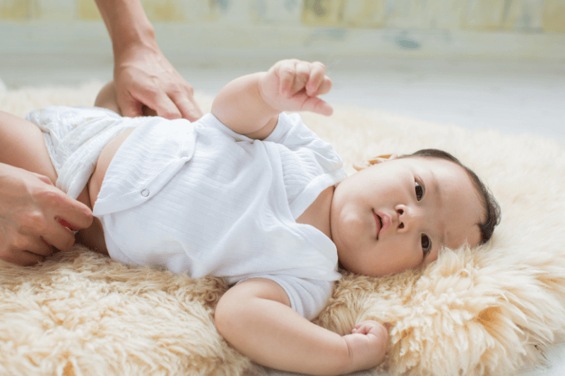 young baby trying to roll on tummy for tummy time